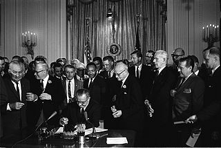 President Lyndon B. Johnson signs the 1964 Civil Rights Act as Martin Luther King, Jr., others look on. Public domain image.