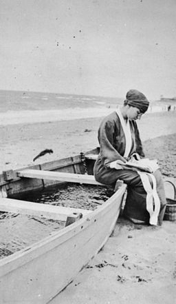 Woman Sitting on a Beached Boat Reading A Book Public Domain Image